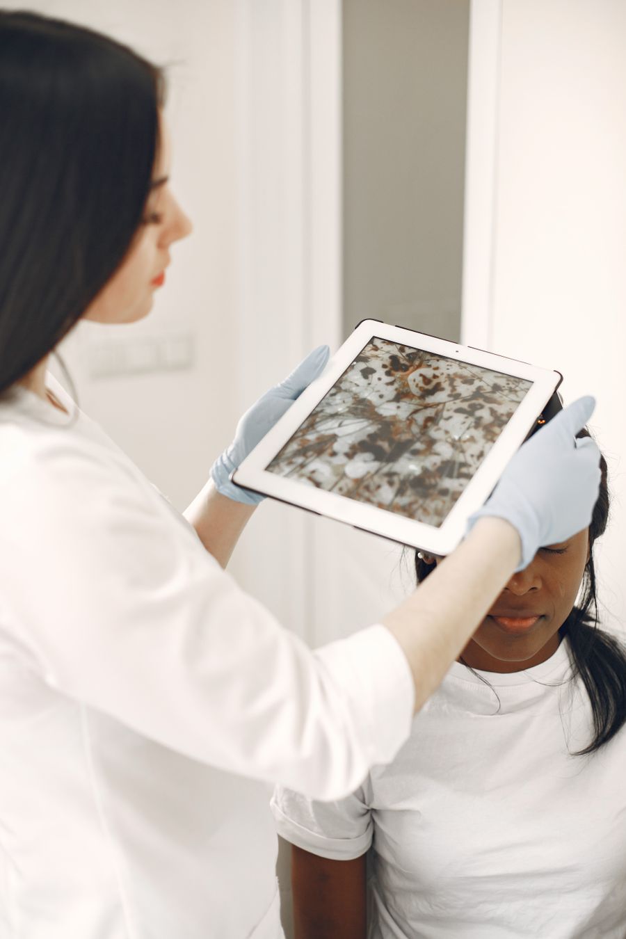 A healthcare professional reviewing a magnified dermoscopy image of skin on a tablet