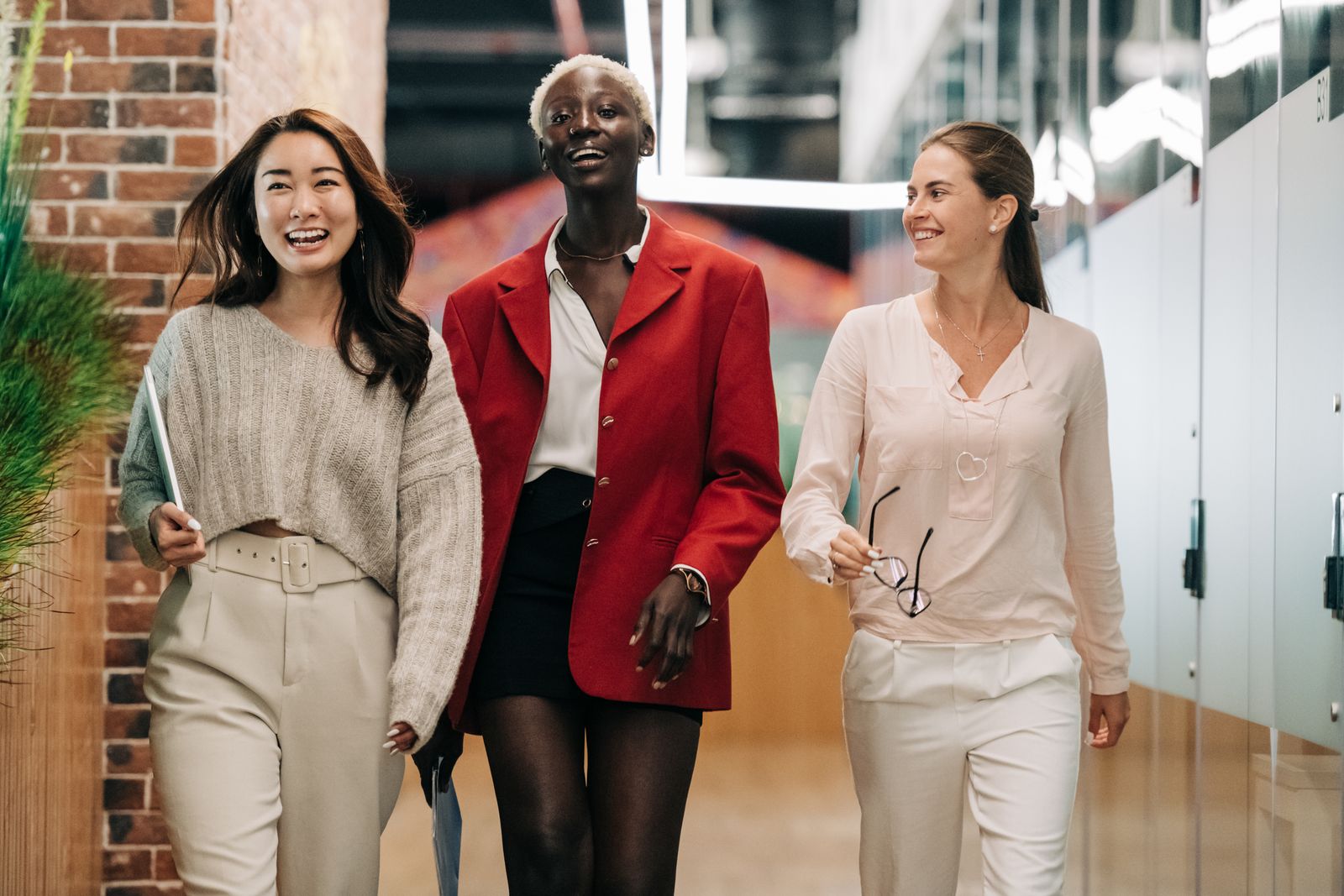 Three professional colleagues walking and talking together in a modern corporate office