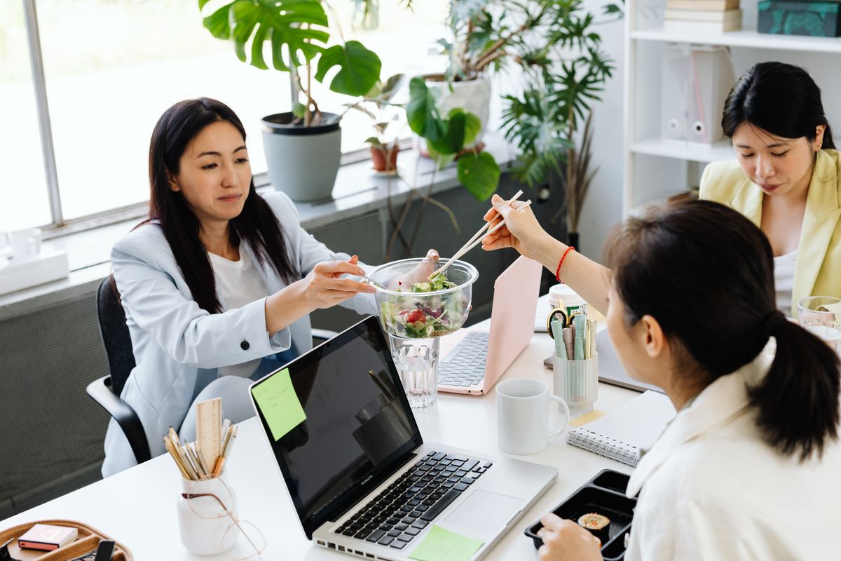 Colleagues sharing a healthy lunch break in a bright, plant-filled office
